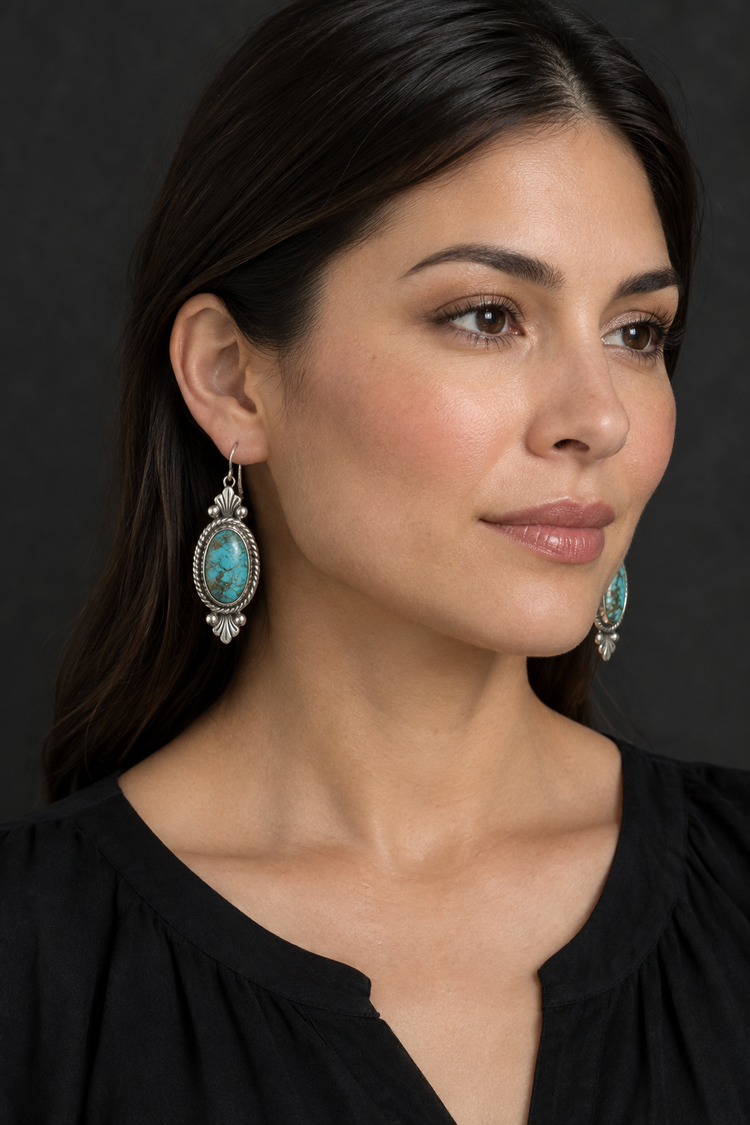 Woman wearing silver and turquoise earrings against a charcoal background